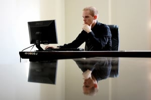 A man in front of a computer, thinking.